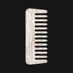 Ivory and beige pearlescent comb with a gold stamped logo on a black background